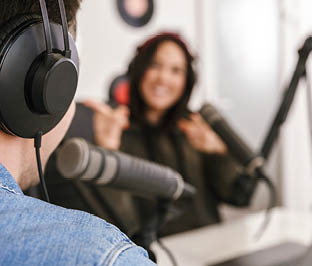 Man and woman in white shirts podcasters interview each other for radio podcast