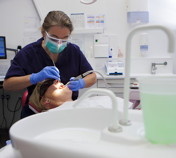 Une femme chirurgien-dentiste pratique des soins sur une patiente - MACSF