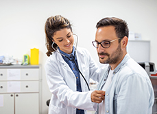 Une interne en médecine ausculte un patient au cabinet - MACSF