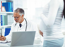 Un médecin rédige un certificat pour une femme enceinte - MACSF