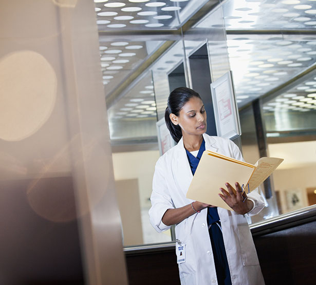 Un médecin debout dans son bureau consulte un dossier - MACSF