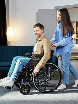 La jeune femme pousse un jeune homme en fauteuil roulant - MACSF