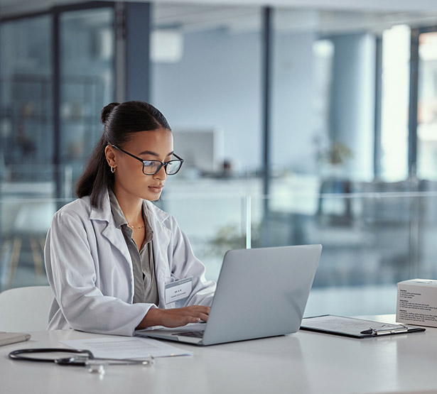 Une femme médecin à son bureau regarde l'écran de son ordinateur - MACSF