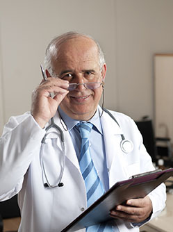 Un médecin senior souriant tient en main un dossier - MACSF
