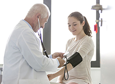 Un médecin prend la tension d'une patiente adolescente - MACSF