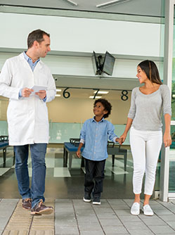 Un enfant marche à côté de sa mère et d'un médecin à l'hôpital - MACSF