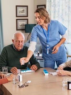 L'aide-soignante donne les médicaments aux patients agés - MACSF