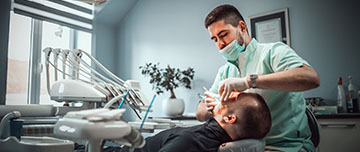 Un chirurgien-dentiste pratique des soins dentaires sur son patient - MACSF