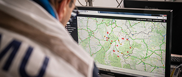 Médecin du centre de régulation du SAMU regardant un carte routière sur l'ordinateur - MACSF