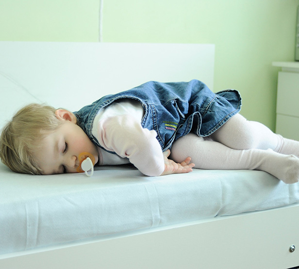 Une petite fille dort sur le bord d'un lit - MACSF