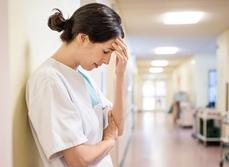 Une infirmière dépitée adossée dans un couloir d'hôpital - MACSF