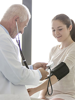 Un médecin prend la tension d'une patiente adolescente - MACSF