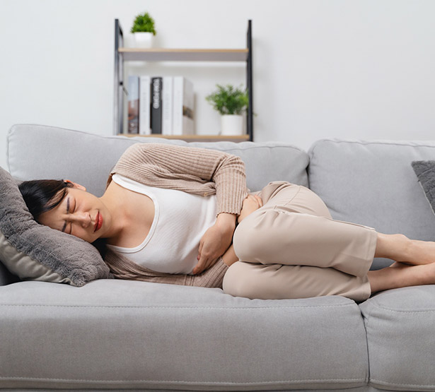 Femme allongée sur le canapé et se tenant le ventre - MACSF