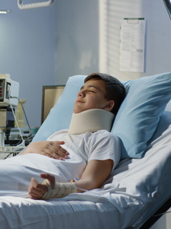 Une infirmière prend des notes auprès d'un jeune patient alité - MACSF