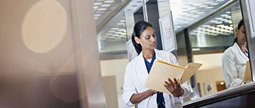 Un médecin debout dans son bureau consulte un dossier - MACSF