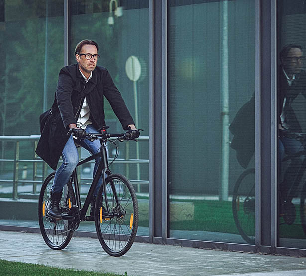 Un homme sur un vélo passe devant des baies vitrées - MACSF