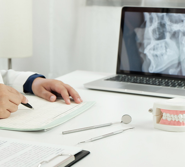 Un chirurgien-dentiste rédige un courrier face à son ordinateur - MACSF
