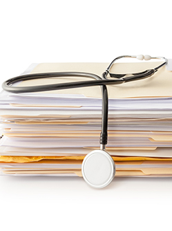 Un stéthoscope posé sur une pile de dossiers médicaux - MACSF