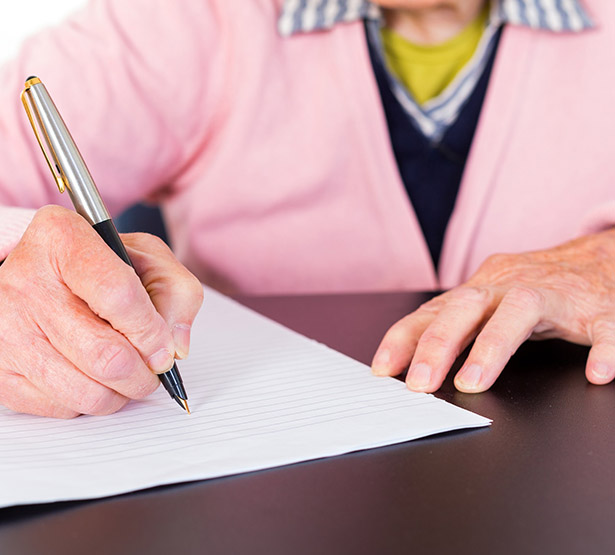 Une femme âgée signe un document - MACSF