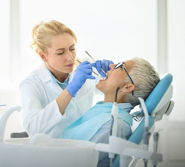 Une femme dentiste réalise des soins sur une patiente - MACSF