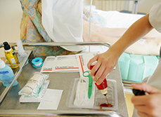 Une infirmière prépare la bétadine pour les soins d'une patiente - MACSF