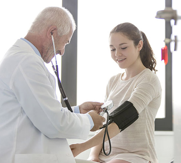 Un médecin prend la tension d'une patiente adolescente - MACSF