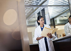 Un médecin debout dans son bureau consulte un dossier - MACSF