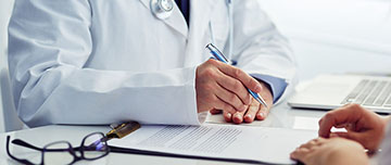 Un médecin complète un document face au patient - MACSF
