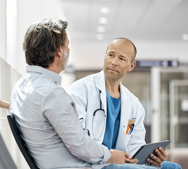 Un médecin discute avec un patient dans le couloir d'un hôpital - MACSF