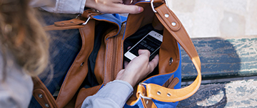 Une femme consulte son téléphone discrètement posé dans son sac à main - MACSF