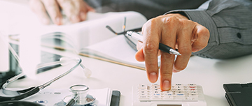 Un médecin tape sur sa calculatrice - MACSF