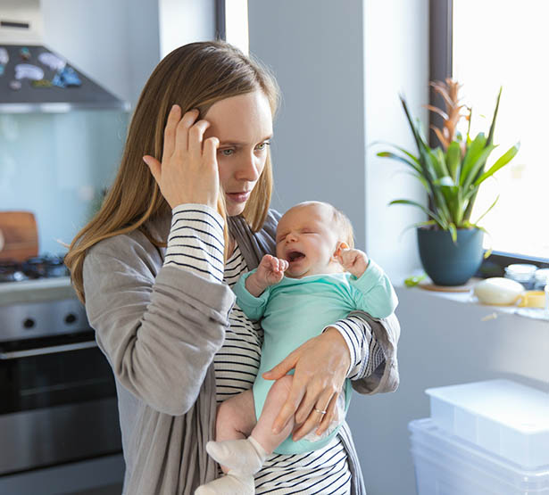 Nourrisson pleure dans les bras de sa maman inquiète - MACSF