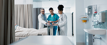 Trois soignants examine le dossier d'un patient dans la chambre de l'hôpital - MACSF