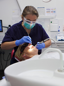 Une femme chirurgien-dentiste pratique des soins sur une patiente - MACSF