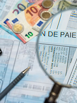 Des bulletins de paie sous une loupe et une calculatrice - MACSF