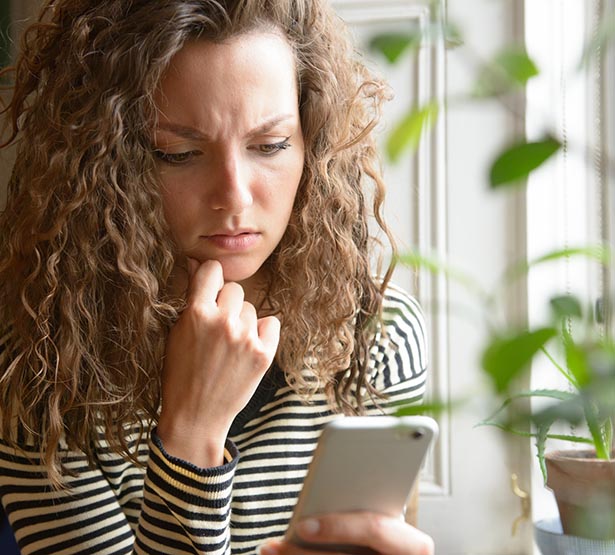 Femme étonnée regarde son téléphone portable - MACSF