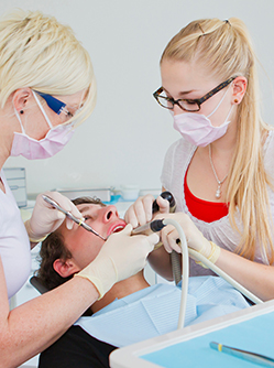 Un chirurgien-dentiste et son assistante dentaire pratiquent des soins sur un patient - MACSF