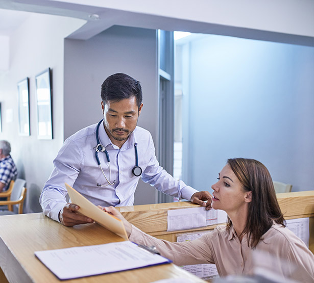 Médecin et réceptionniste discutant du dossier médical – MACSF
