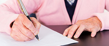Une femme âgée signe un document - MACSF