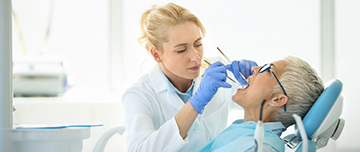 Une femme dentiste réalise des soins sur une patiente - MACSF