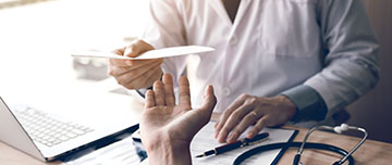 Un médecin tend un document au patient - MACSF