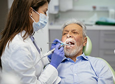 Une femme chirurgien-dentiste soigne un patient - MACSF