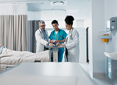 Trois soignants examine le dossier d'un patient dans la chambre de l'hôpital - MACSF