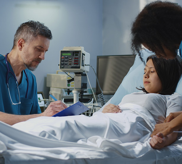 Jeune femme alitée à l'hôpital, entourée de deux soignants - MACSF