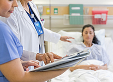 Un médecin et une infirmière regardent le dossier d'une patiente alitée - MACSF