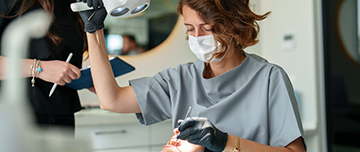Une femme chirurgien-dentiste pratique des soins sur une patiente - MACSF