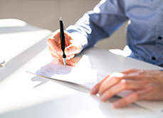 Un homme remplissant un chèque - MACSF