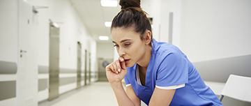 Une soignante assise inquiète assise dans le couloir de l'hôpital - MACSF