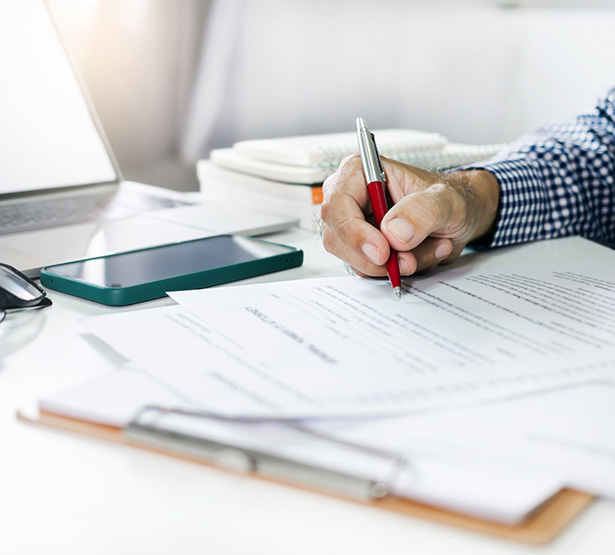 Main d'homme signant un document sur le bureau - MACSF