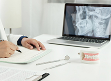 Un chirurgien-dentiste rédige un courrier face à son ordinateur - MACSF